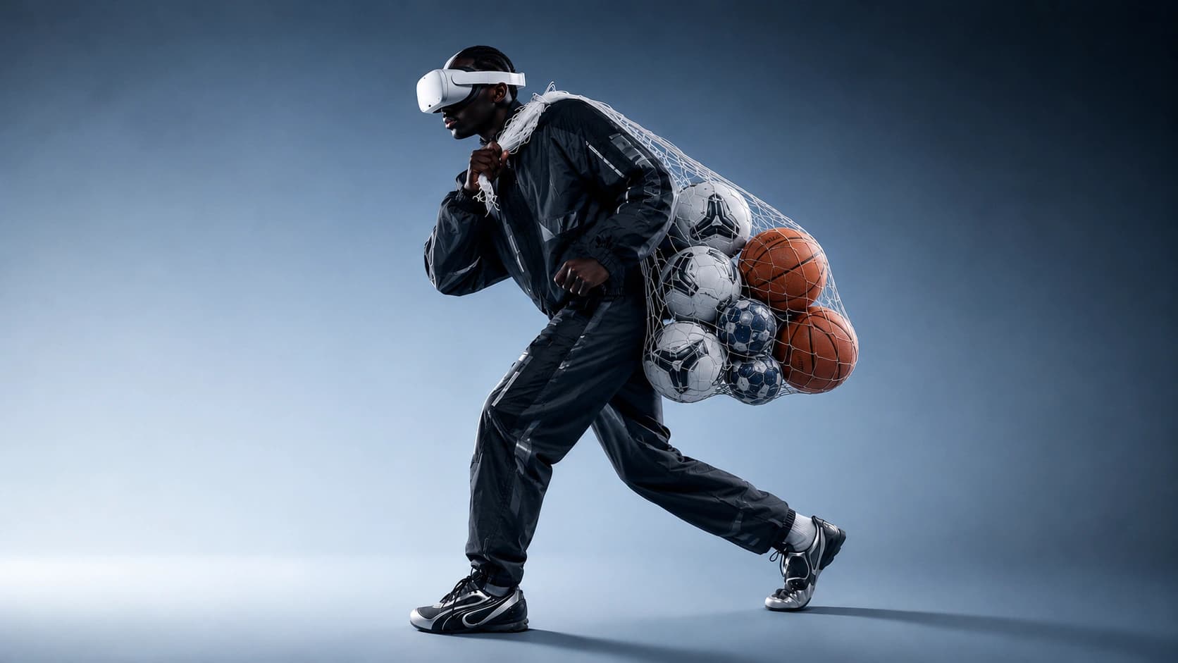 Man carrying a net full of soccer and basketballs