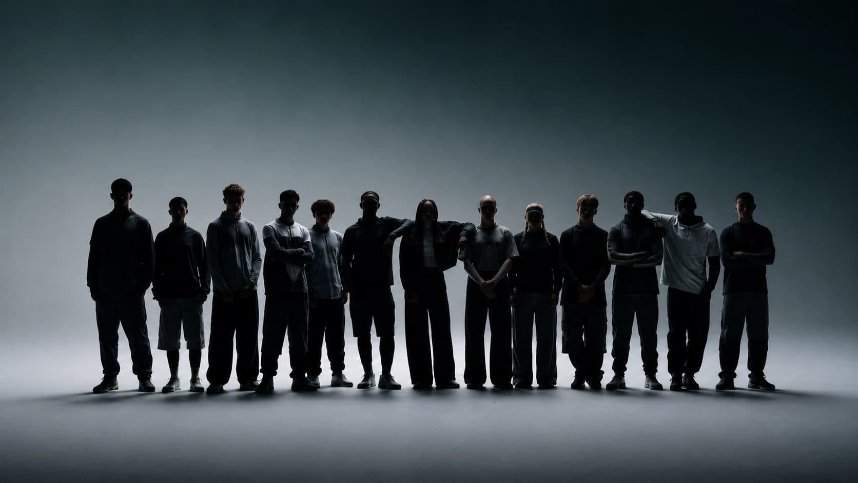 A long line of athletes standing shoulder to shoulder in silhouette against a lit studio backdrop